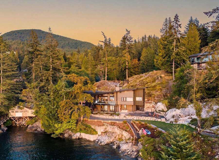 Experience luxury waterfront living in this stunning modern home nestled amidst a lush forest setting.