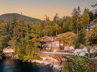 Experience luxury waterfront living in this stunning modern home nestled amidst a lush forest setting.