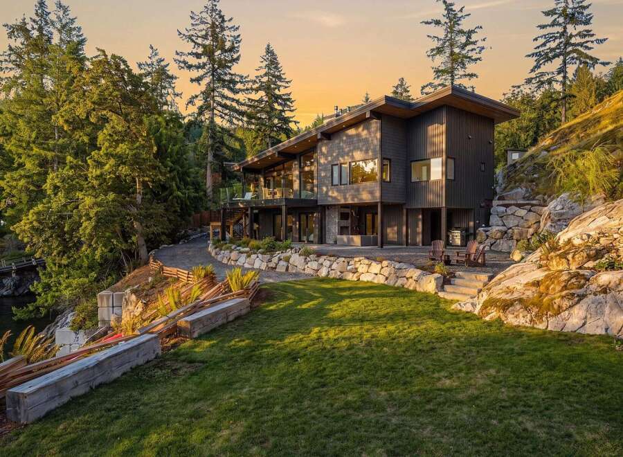 Experience luxury living in this stunning modern home nestled amidst lush greenery and rocky terrain.