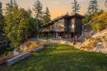Experience luxury living in this stunning modern home nestled amidst lush greenery and rocky terrain.