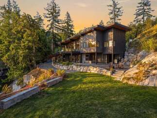 Experience luxury living in this stunning modern home nestled amidst lush greenery and rocky terrain.