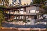Experience modern luxury in this stunning hillside home, featuring expansive glass windows and a sleek, contemporary design.