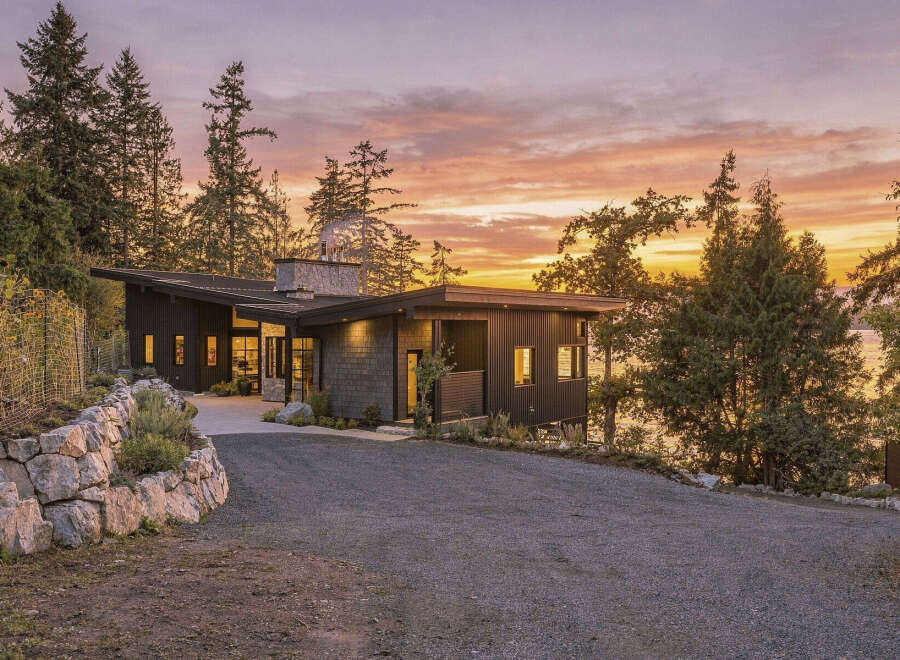 Experience modern luxury in this stunning home, featuring a striking dark exterior and a unique asymmetrical roofline.