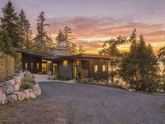 Experience modern luxury in this stunning home, featuring a striking dark exterior and a unique asymmetrical roofline.