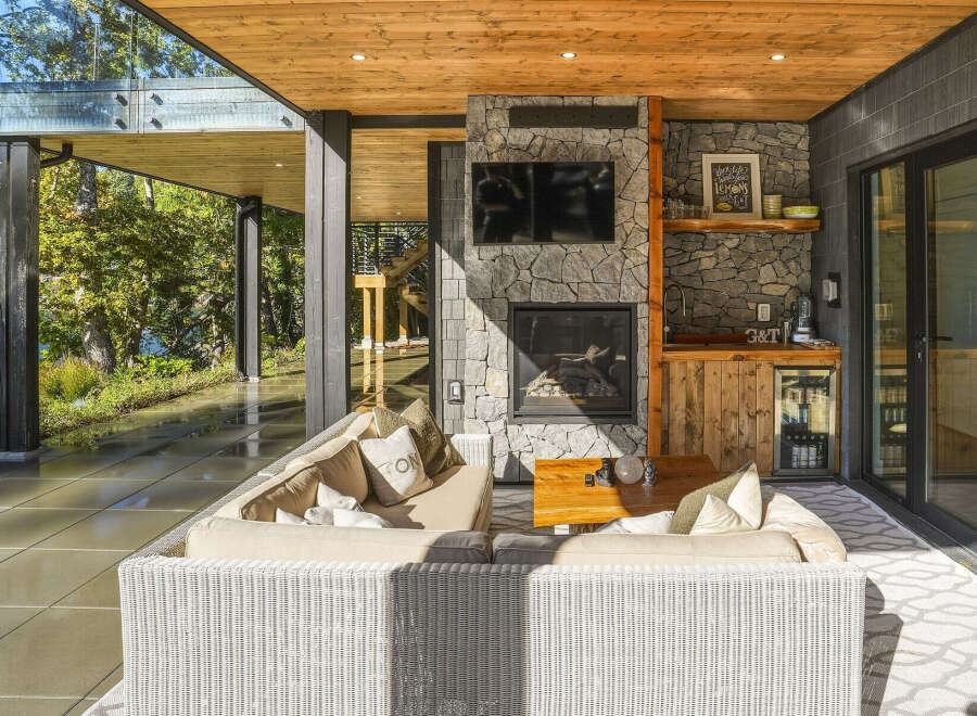 Experience luxurious outdoor living with this stunning covered patio, featuring a cozy seating area centered around a stone fireplace and a convenient wet bar.