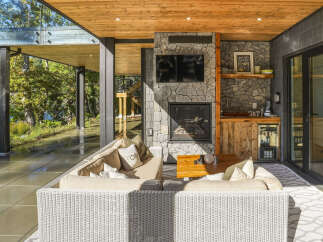 Experience luxurious outdoor living with this stunning covered patio, featuring a cozy seating area centered around a stone fireplace and a convenient wet bar.