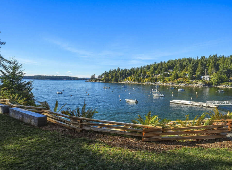 Enjoy breathtaking waterfront views from this stunning property, featuring a serene bay dotted with boats and a lush, tree-lined coastline.