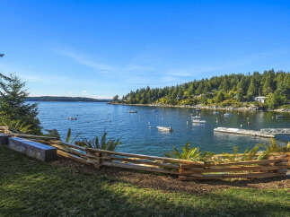 Enjoy breathtaking waterfront views from this stunning property, featuring a serene bay dotted with boats and a lush, tree-lined coastline.