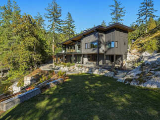 Discover this stunning modern home nestled amidst lush greenery and rocky terrain, offering breathtaking water views.