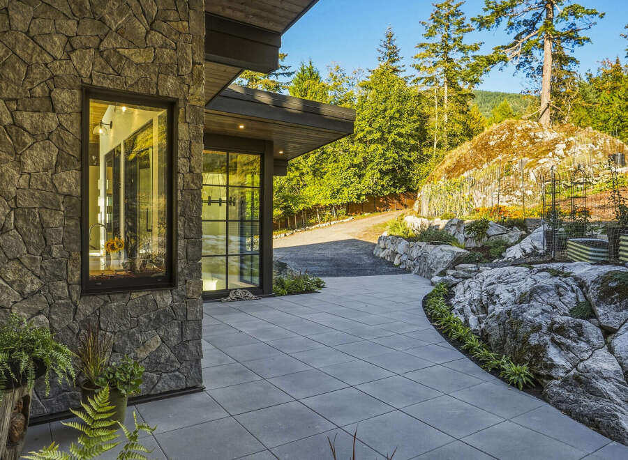 Experience modern luxury with this stunning home featuring a striking stone facade and expansive glass windows that invite natural light.