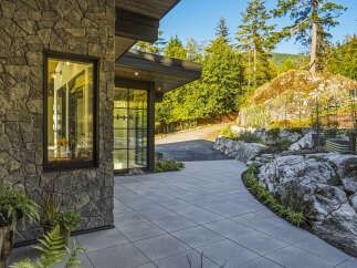 Experience modern luxury with this stunning home featuring a striking stone facade and expansive glass windows that invite natural light.