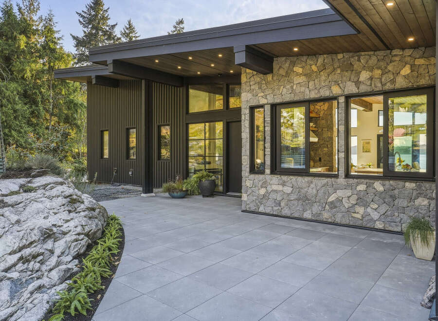 Experience modern luxury in this stunning home featuring a striking stone facade and sleek vertical siding.