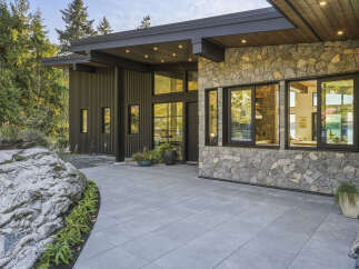 Experience modern luxury in this stunning home featuring a striking stone facade and sleek vertical siding.