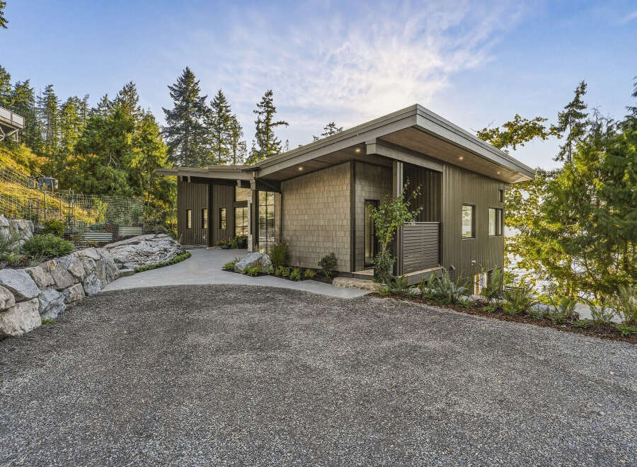 This modern home boasts a unique architectural design with a mix of vertical metal siding and natural stone accents.