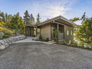 This modern home boasts a unique architectural design with a mix of vertical metal siding and natural stone accents.