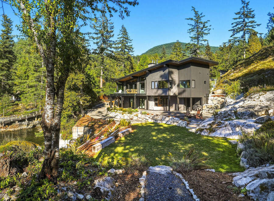 Experience modern luxury in this stunning contemporary home nestled amidst lush greenery and rocky terrain.