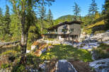 Experience modern luxury in this stunning contemporary home nestled amidst lush greenery and rocky terrain.