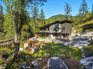 Experience modern luxury in this stunning contemporary home nestled amidst lush greenery and rocky terrain.