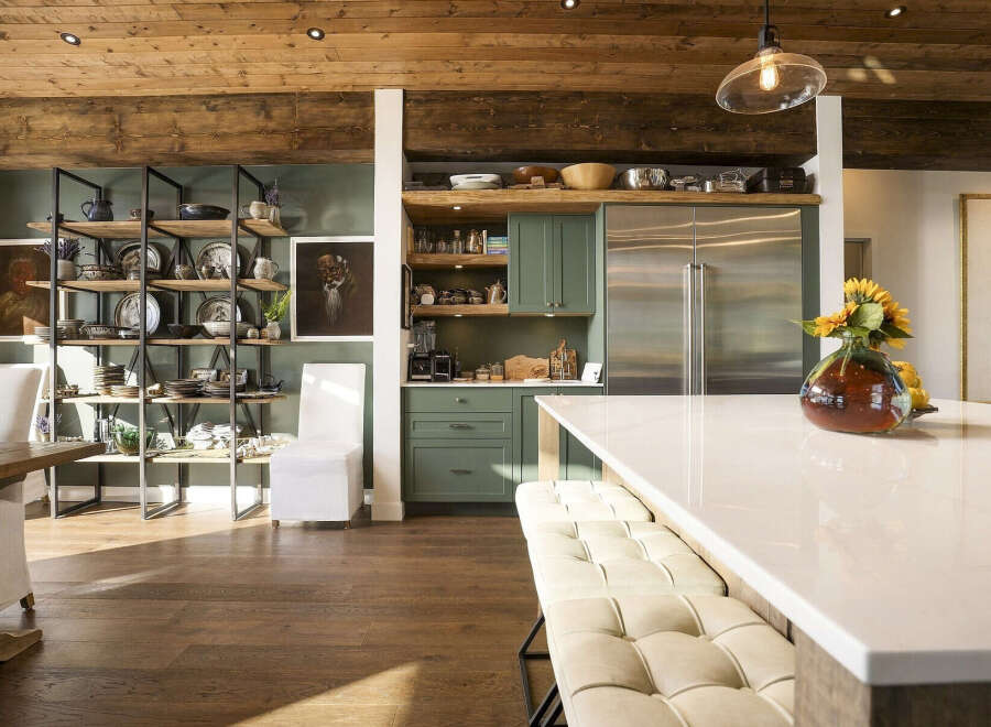 This stunning kitchen boasts a rustic yet modern aesthetic, featuring exposed wooden beams on the ceiling and a sleek, large stainless steel refrigerator.