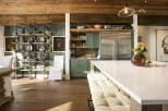 This stunning kitchen boasts a rustic yet modern aesthetic, featuring exposed wooden beams on the ceiling and a sleek, large stainless steel refrigerator.