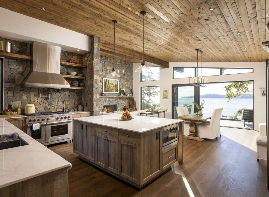 Experience luxury living in this stunning kitchen and dining area, boasting a large stone fireplace and breathtaking ocean views.