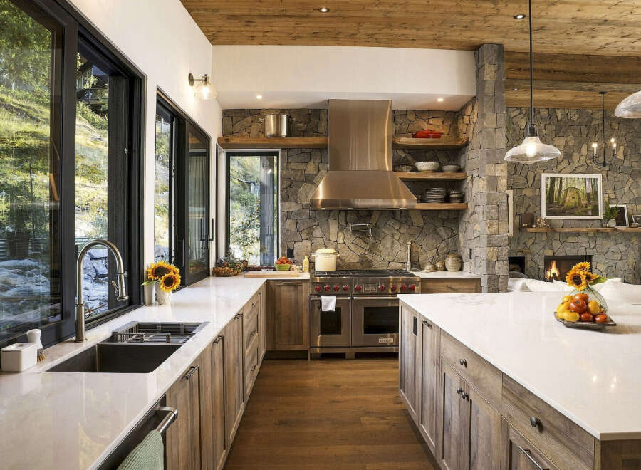 Experience rustic luxury in this stunning mountain kitchen, featuring a professional-grade Wolf range and a dramatic stone accent wall.