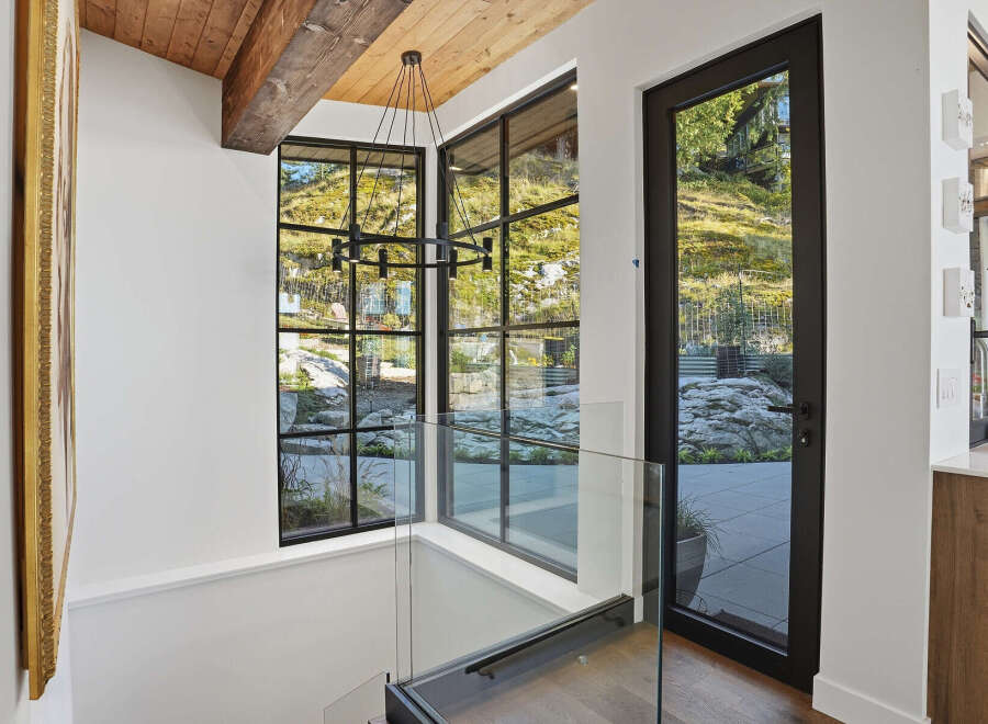 Experience modern living with stunning natural views through expansive black-framed windows.