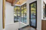 Experience modern living with stunning natural views through expansive black-framed windows.
