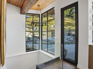 Experience modern living with stunning natural views through expansive black-framed windows.