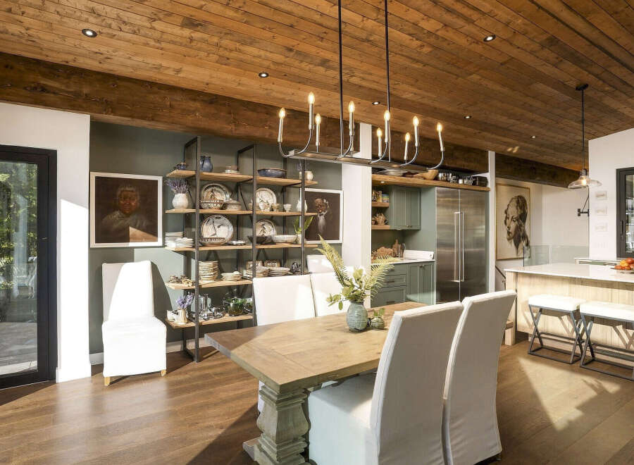 This spacious dining room boasts a rustic wooden ceiling and a modern chandelier, creating a warm and inviting atmosphere.