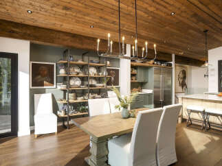 This spacious dining room boasts a rustic wooden ceiling and a modern chandelier, creating a warm and inviting atmosphere.