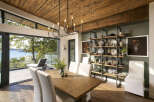 Experience luxurious waterfront living in this stunning dining room, featuring a rustic wooden table and chairs complemented by a modern black chandelier.