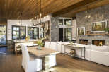 Experience rustic luxury in this open-concept living space, featuring a gourmet kitchen with a large island and a cozy living area centered around a grand stone fireplace.