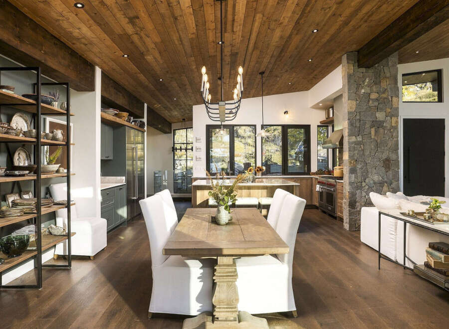 Experience rustic elegance in this open-concept living space, featuring a stunning wood-planked ceiling and exposed beams that create a warm, inviting atmosphere.