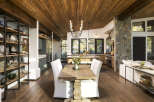 Experience rustic elegance in this open-concept living space, featuring a stunning wood-planked ceiling and exposed beams that create a warm, inviting atmosphere.