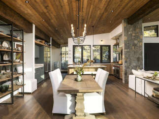 Experience rustic elegance in this open-concept living space, featuring a stunning wood-planked ceiling and exposed beams that create a warm, inviting atmosphere.
