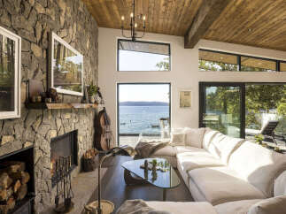 Experience breathtaking waterfront living in this stunning modern home, featuring a dramatic stone fireplace and expansive windows that frame panoramic ocean views.