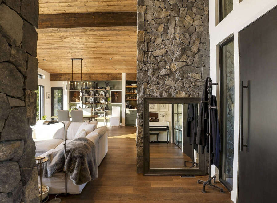 Experience rustic elegance in this spacious living area, featuring a stunning floor-to-ceiling stone fireplace and exposed wooden beams that add warmth and character.