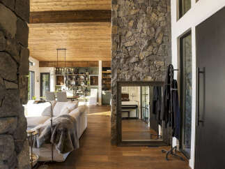 Experience rustic elegance in this spacious living area, featuring a stunning floor-to-ceiling stone fireplace and exposed wooden beams that add warmth and character.
