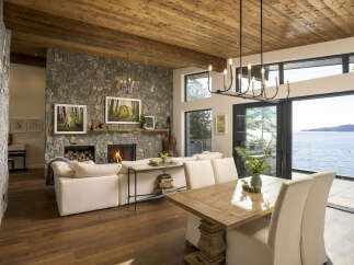 Experience luxurious waterfront living in this stunning home featuring a grand stone fireplace and a rustic wood-paneled ceiling.