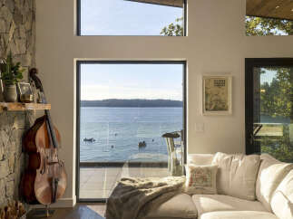 Experience breathtaking waterfront living in this stunning modern home, featuring expansive windows that frame panoramic ocean views and a lush treeline.