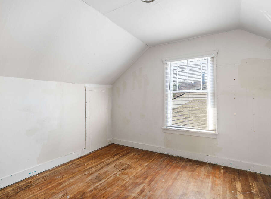 This attic room features a sloped ceiling and a large window that floods the space with natural light.