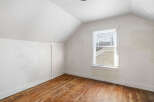 This attic room features a sloped ceiling and a large window that floods the space with natural light.