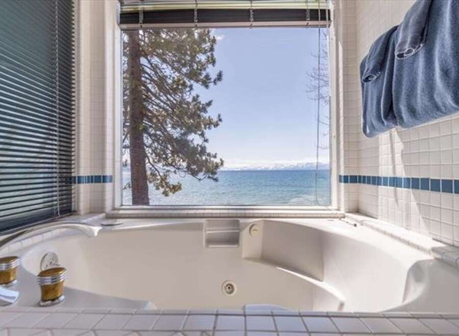 Indulge in relaxation with this luxurious jetted bathtub, offering stunning panoramic views of a serene lake and distant snow-capped mountains.