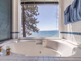 Indulge in relaxation with this luxurious jetted bathtub, offering stunning panoramic views of a serene lake and distant snow-capped mountains.