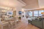 Experience breathtaking lake views from this stunning living and dining area, featuring a cozy fireplace and elegant chandelier.