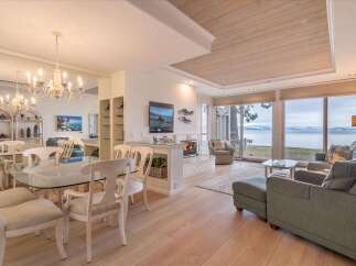 Experience breathtaking lake views from this stunning living and dining area, featuring a cozy fireplace and elegant chandelier.