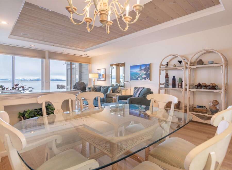 Enjoy breathtaking lake and mountain views from this stunning dining area, featuring a glass-top table and comfortable seating.