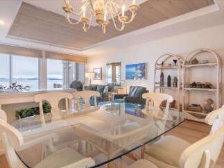 Enjoy breathtaking lake and mountain views from this stunning dining area, featuring a glass-top table and comfortable seating.