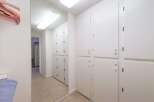 This hallway features a full-length mirror that reflects a row of white cabinets, offering ample storage space.
